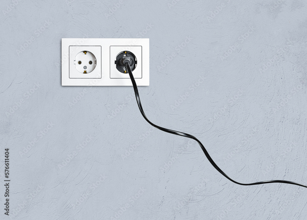 electrical socket and plug in it, against the background of a gray wall electrical socket and plug in it, against the background of a gray wall