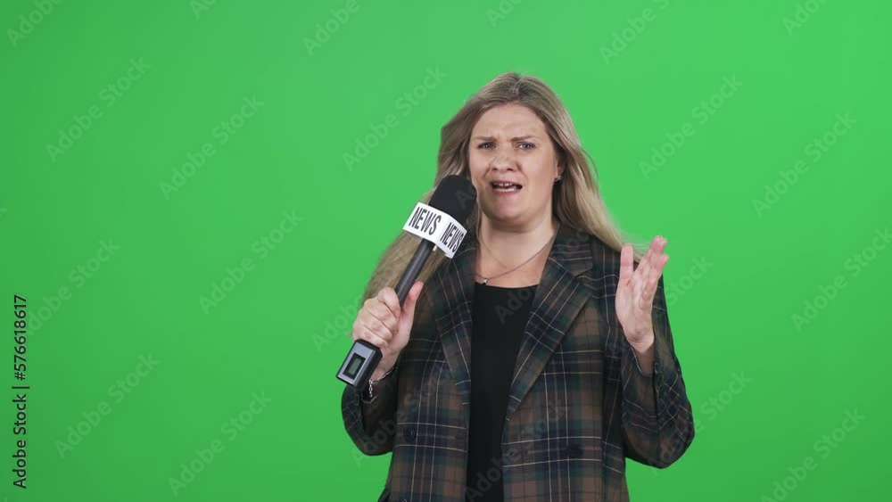 Windy weather, woman reporter in suit looks into the camera and speaks into a microphone on a green background, template for TV news agencies, journalist at work, chromakey. Windy weather, woman reporter in suit looks into the camera and speaks into a microphone on a green background, template for TV news agencies, journalist at work, chromakey.