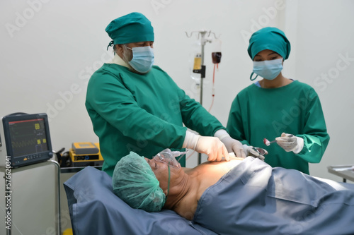 Group of surgeons and nurse in surgical green gown working at operating room of the hospital. Medical Team performing Surgical operation.