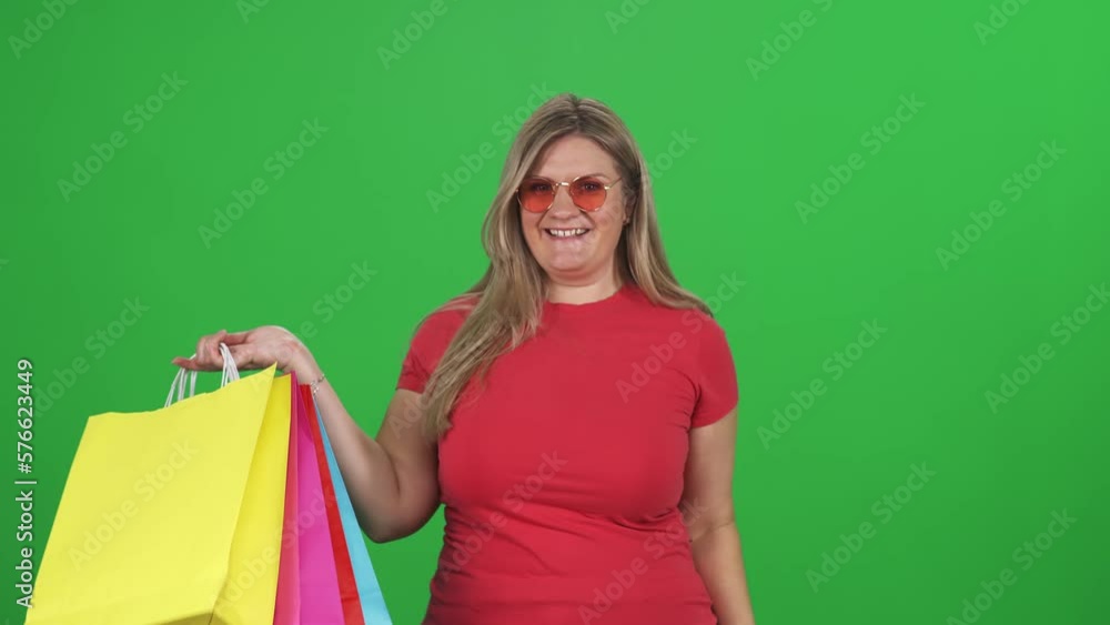 Woman in a red t shirt makes successful purchases, a plus size model enjoys successful purchases on a green background. Woman in a red t shirt makes successful purchases, a plus size model enjoys successful purchases on a green background.