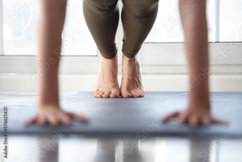 Yogini girl standing in plank at home. Young woman doing yoga exercises on mat in the morning © hurricanehank