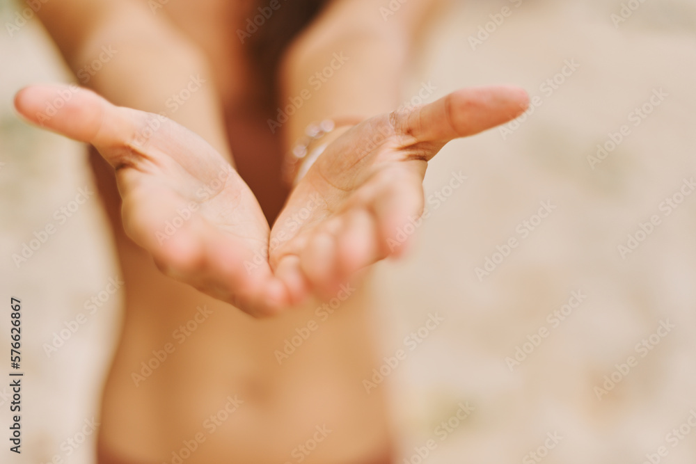 Naklejka premium Tanned girl in bikini with her arms outstretched forward, gesture of giving energy, stands on beach