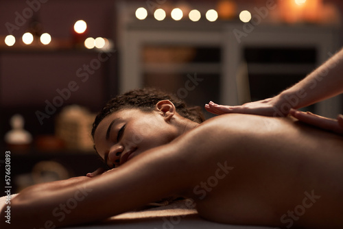 Young woman enjoying relaxing back massage in spa salon