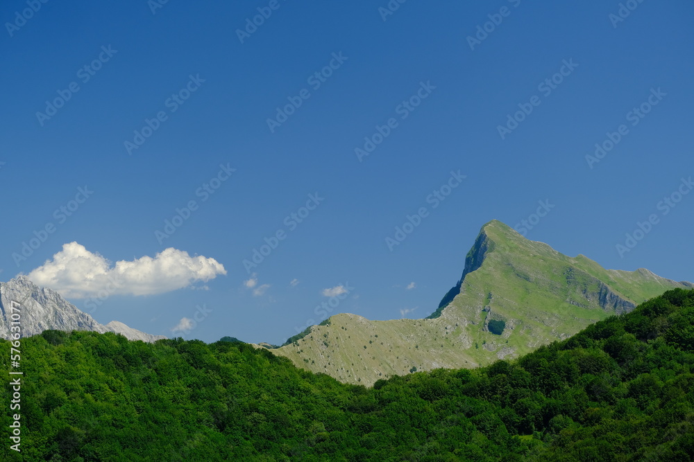 Monte Sagro. Panorama of mountains. Pizzo d'Uccello, Monte Sagro and the Apuan Alps between green woods and blue sky. Apuan Alps, Tuscany, Italy. 