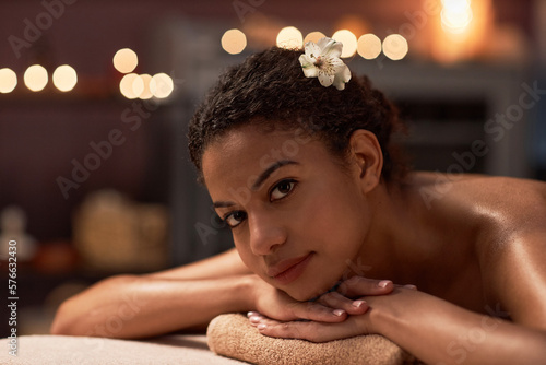 Young woman with flower in hair relaxing after getting spa massage