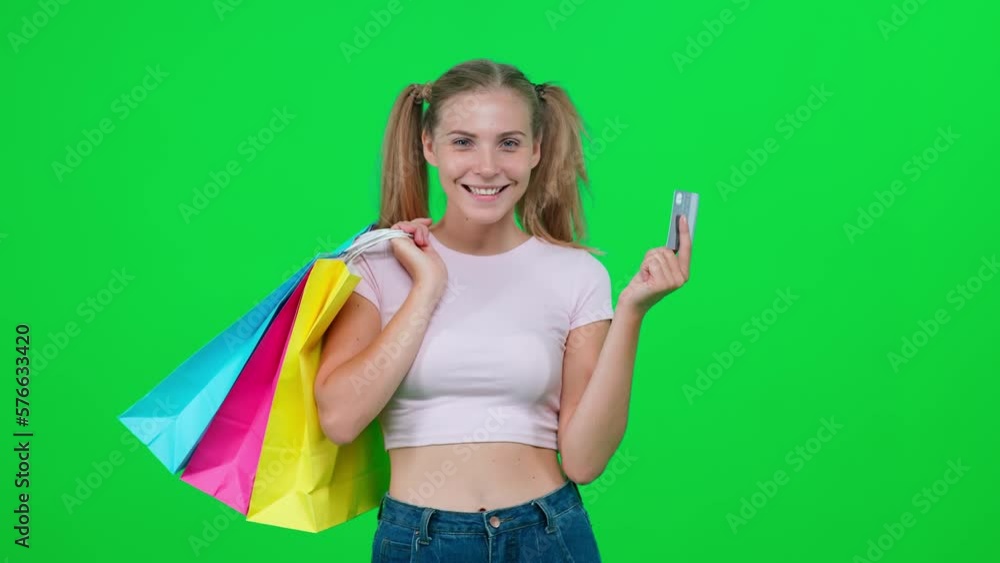 Shopping, pretty woman in a white t shirt makes successful purchases using a credit card, a stylish caucasian woman enjoys successful purchases on a green background. Shopping, pretty woman in a white t shirt makes successful purchases using a credit card, a stylish caucasian woman enjoys successful purchases on a green background.