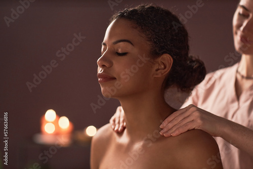 Relaxed young woman enjoying shoulders massage with natural oils