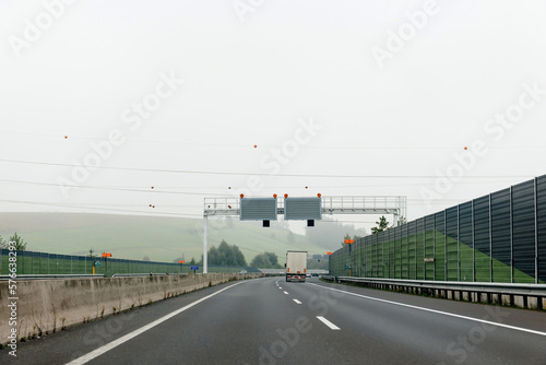Highway in the rural Europe with lonely trailer cargo truck driving fast on the multiple lane highway - rear view