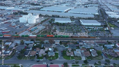 Aerial view of a freight cargo stacked train pulling its load through a neighborhood and Industrial park in South Montebello, California, USA. photo
