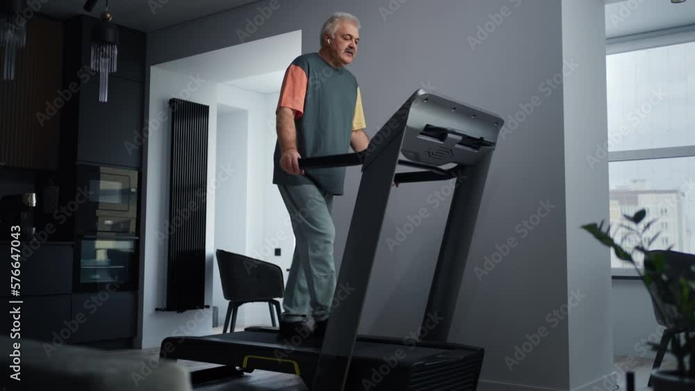 Modern Mature Man Training Alone On Treadmill, Home Fitness For Saving Health, Cardio Workout Modern Mature Man Training Alone On Treadmill, Home Fitness For Saving Health, Cardio Workout