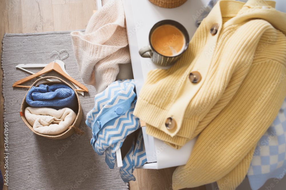 Morning home routine. Woman organizing clothes, many knitted sweaters ...