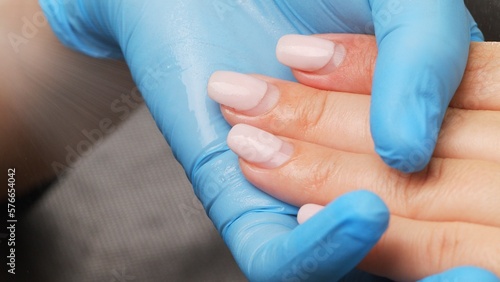 Manicurist sprays antiseptic on the nails before treating old  acrylic nails. Treatment of nails with a disinfectant before manicure. Applying a disinfectant to women s hands.