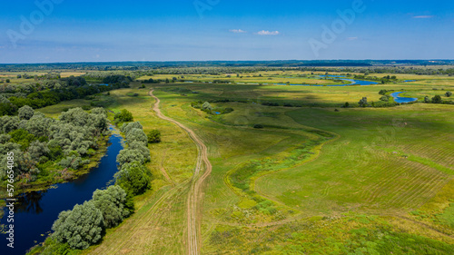 Wide green valley with a small river . Green meadows. Top view over beauty nature. Aerial view of a beautiful summer hilly landscape.