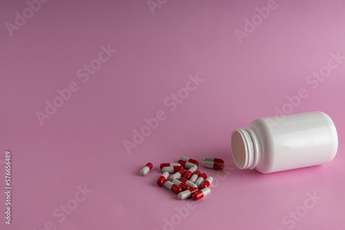 A jar for medicine on a pink background.