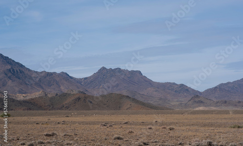 Rocky desert landscape with sparse vegetation and mountains peaks in a blue haze. Typical landscape near at Nepal Tibet border. Flat dry desert with mountains.