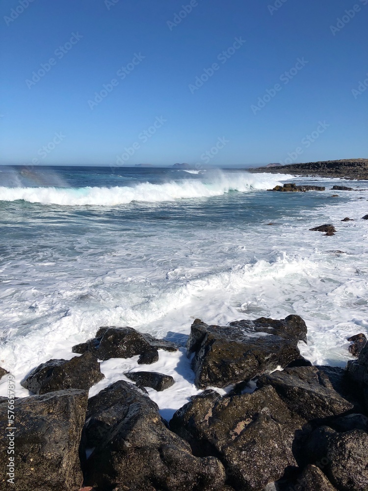 Ocean view background. Water splash from waves on rocky beach. Lanzarote island vertical wallpaper.