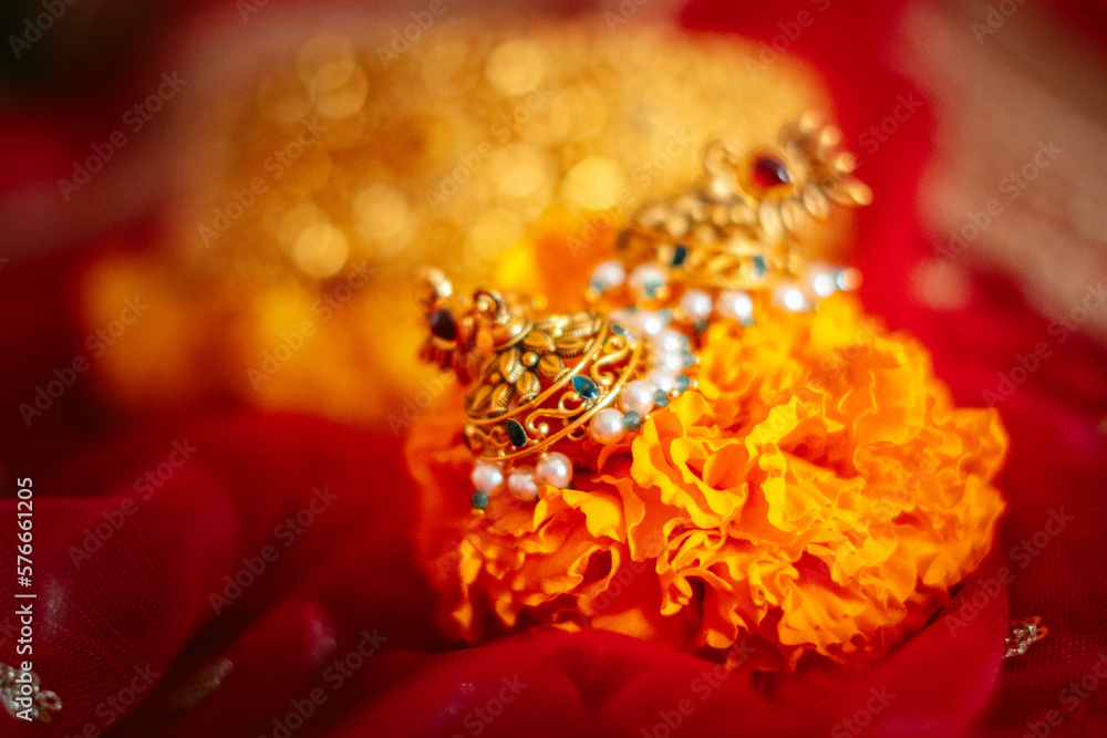 Gold earrings jewelry with red bridal wedding dress in background. Luxury necklace, Indian Traditional Jewellery Necklace. Royal Indian wedding concept.