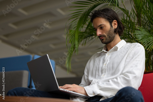 portrait d'un jeune homme employé de bureau ou homme d'affaires qui travaille sur un ordinateur portable, assis dans un bureau confortable photo