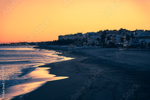 Sunset in Torremolinos beach in winter. Waves and buildings in Costa del sol in Spain. Mediterranean sea. 