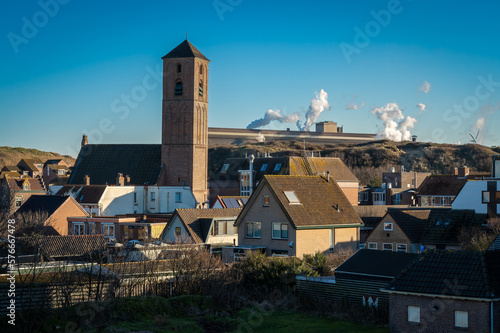 Dutch village Wijk aan Zee on the coast of the North Sea, view of the church and heavy industry in the background photo