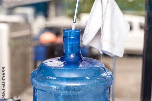 A cylindrical 20 liter HPDE water container being refilled with purified H2O. A purified water refilling station business. photo