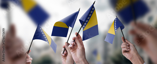 A group of people holding small flags of the Bosnia and Herzegovina in their hands