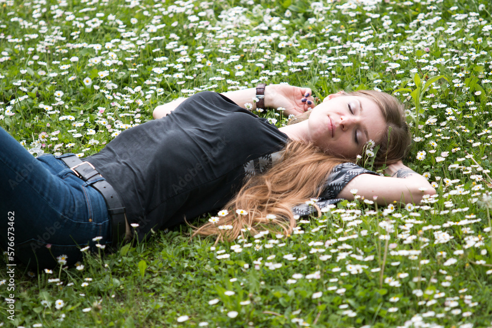 smiling young woman lying on a lawn with daisies in summer field smiling young woman lying on a lawn with daisies in summer field