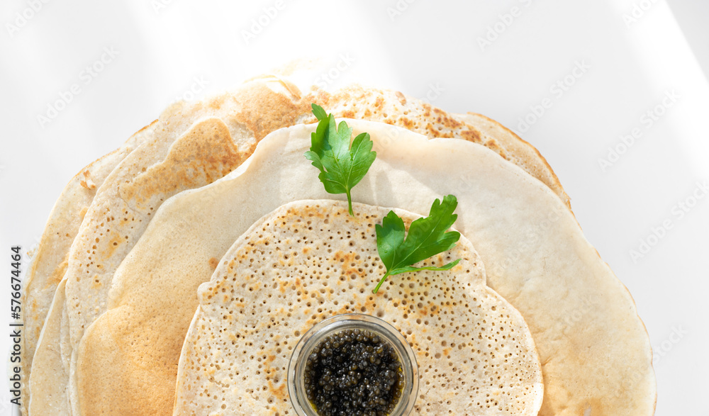 served pancake with black caviar, parsley