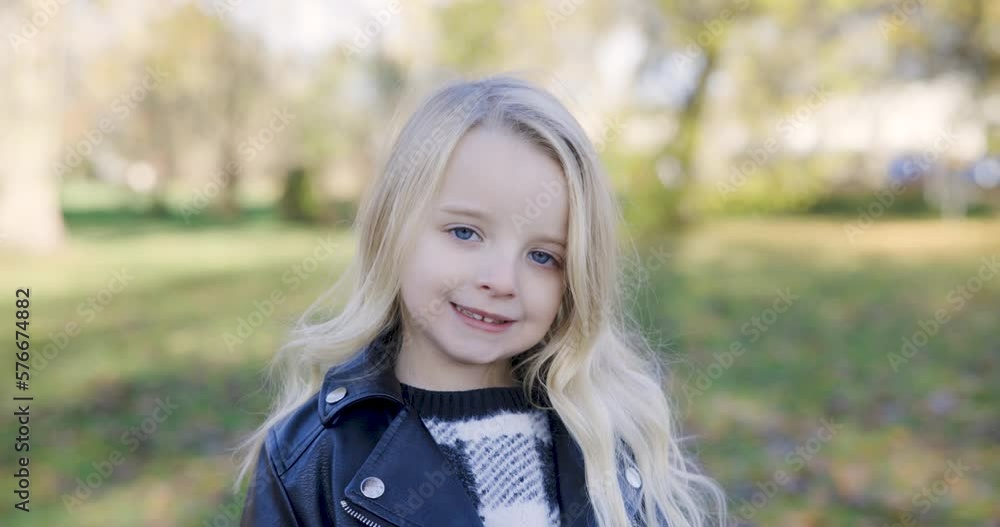 Portrait of blonde girl at park, smiling and looking at camera Portrait of blonde girl at park, smiling and looking at camera