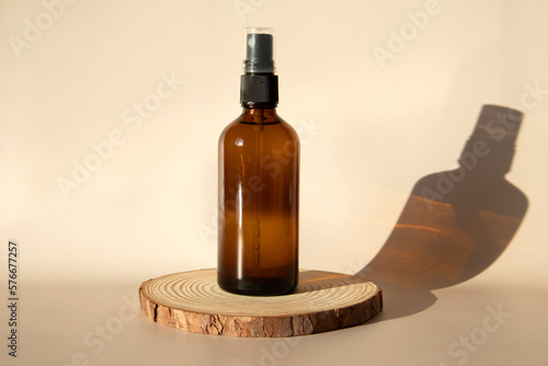 Brown glass bottle with spray moc ap on a beige background on a wooden catwalk in the sun.