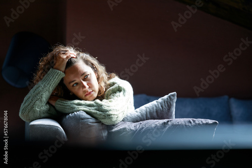 Billede på lærred Depressed young woman on sofa at home