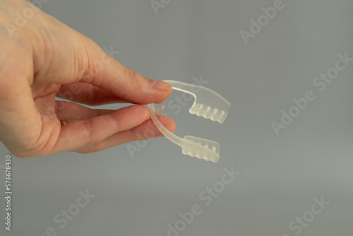 Nighttime dental care. Keeping teeth healthy overnight. Mouth guard in a woman's hand on a beige background photo