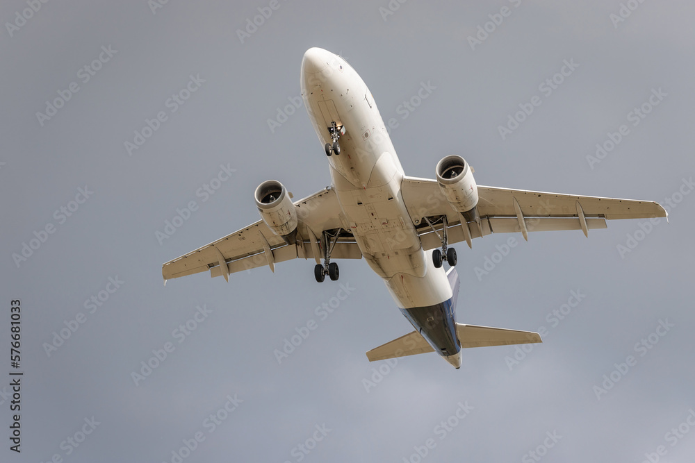 Fototapeta premium Flying airplane from below. Grey background.