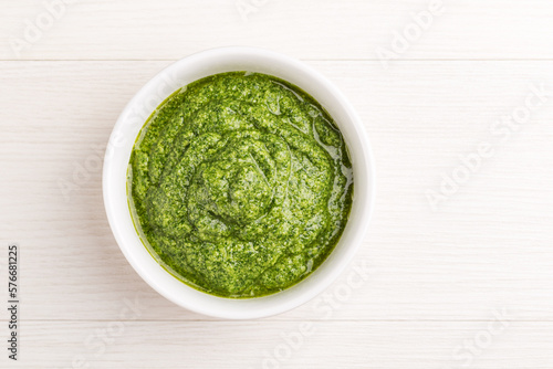 Homemade pesto sauce with curly kale in a white bowl on a light wooden background. Healthy eating concept. Superfoods. Organic food. Top view.