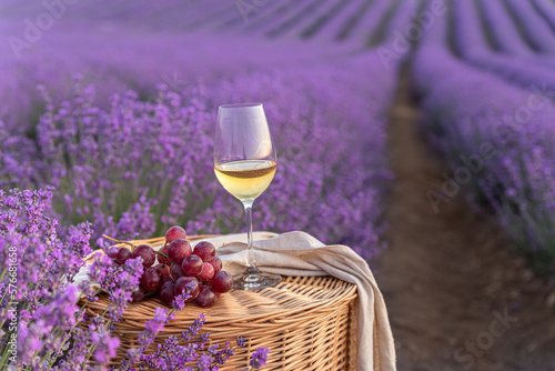 Glass of white wine in a lavender field. Violet flowers on the background.