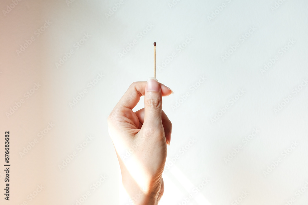 Hand with a match or matchstick on white cement wall. Hand with a match or matchstick on white cement wall.