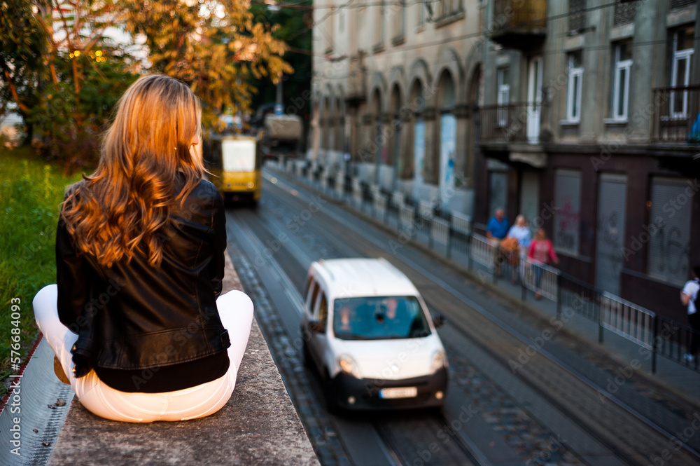 Fototapeta premium Smiling woman in the city street wearing black leather jacket and white pants and sunglasses