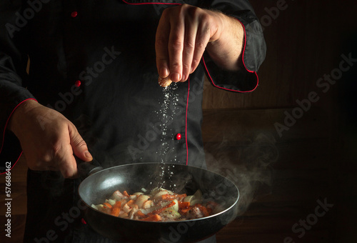 Chef adds salt to a steaming hot pan. Menu idea for a hotel with advertising space. Asian national cuisine. Space for restaurant menu or recipe