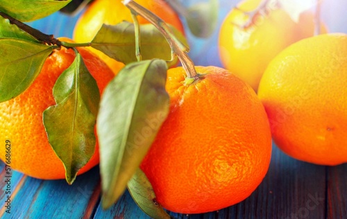 Close-up of ripe orange tangerines with green foxes on a wooden table. Selective focus.