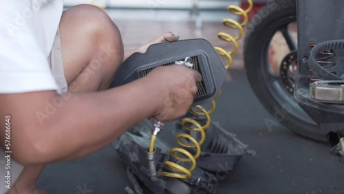 Hands of a mechanic cleaning automatic motorcycle spare parts photo