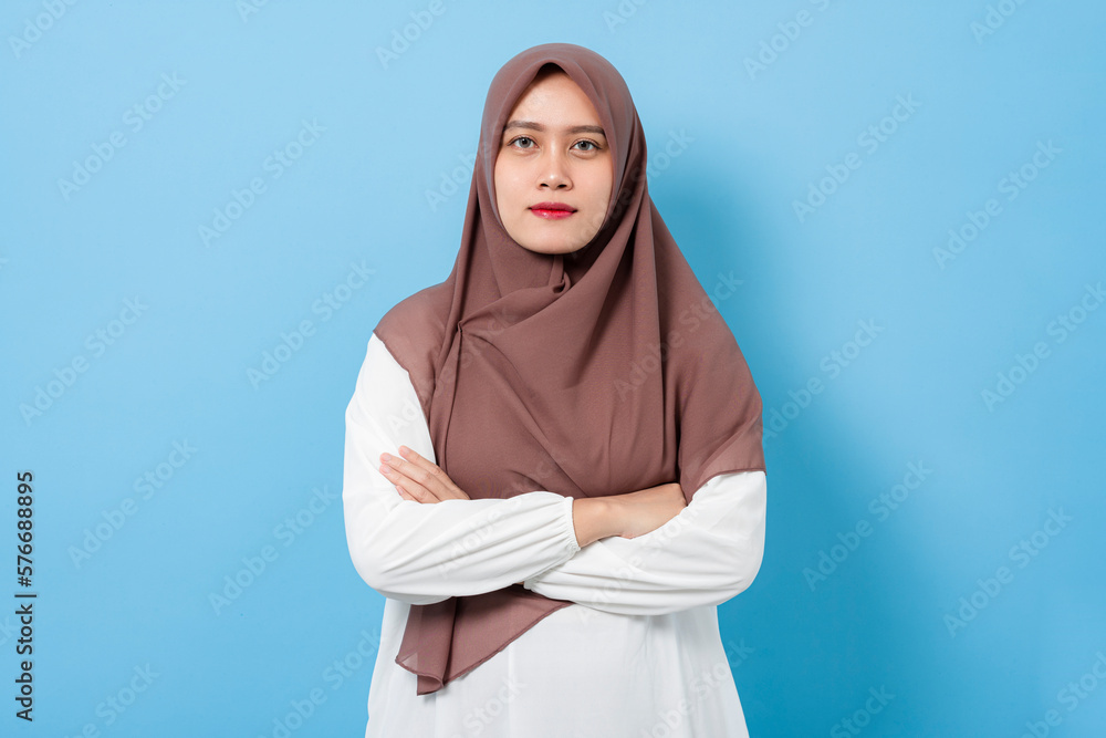 Portrait of smiling confident muslim woman isolated on blue background Portrait of smiling confident muslim woman isolated on blue background