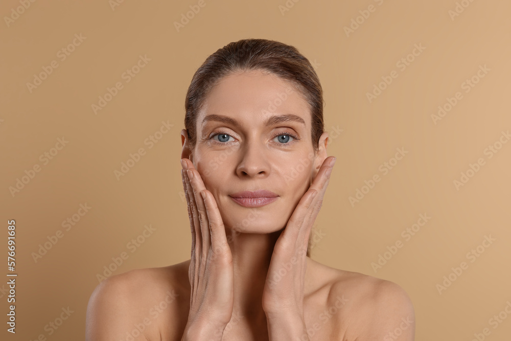 Woman massaging her face on beige background Woman massaging her face on beige background