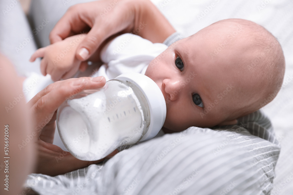 Mother feeding her little baby from bottle, closeup Mother feeding her little baby from bottle, closeup