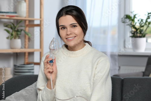 Happy young woman with nebulizer at home photo