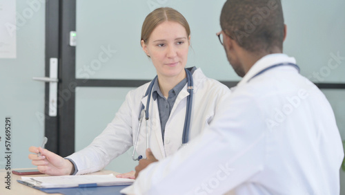 African Doctor and Female Doctor Discussing Patient in Clinic