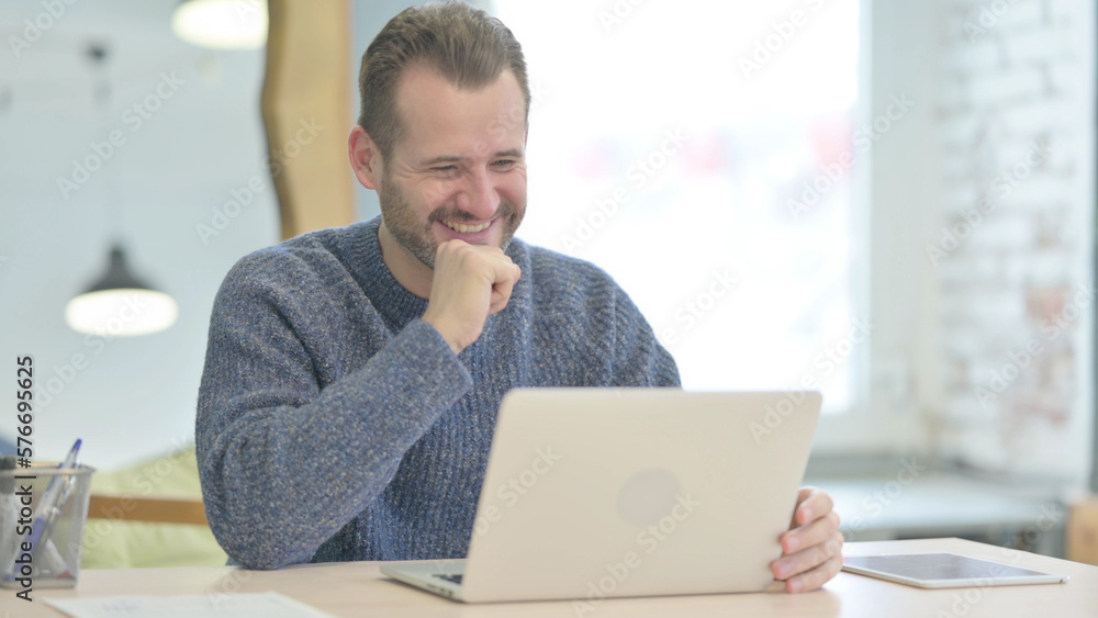 Middle Aged Man Celebrating Online Success on Laptop in Office Middle Aged Man Celebrating Online Success on Laptop in Office