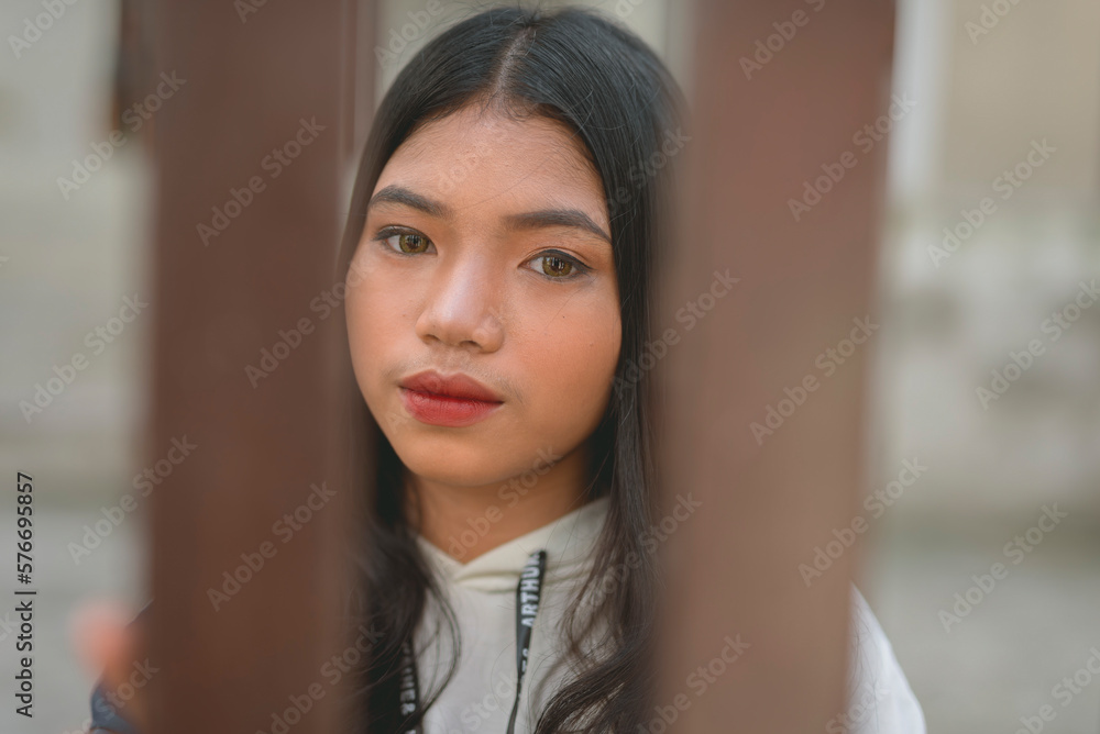 A pretty filipino woman as seen behind the fence of a gated house. A pretty filipino woman as seen behind the fence of a gated house.