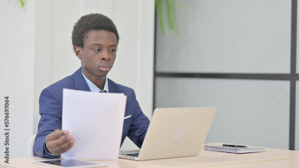 African Businessman Working on Laptop and Documents African Businessman Working on Laptop and Documents