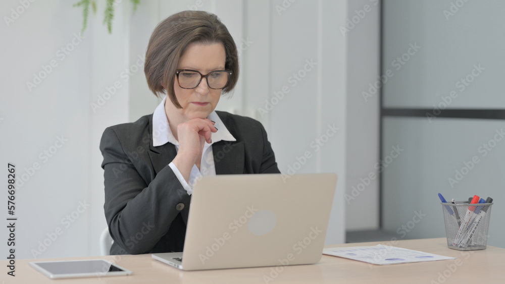 Old Businesswoman Thinking while Working on Laptop Old Businesswoman Thinking while Working on Laptop