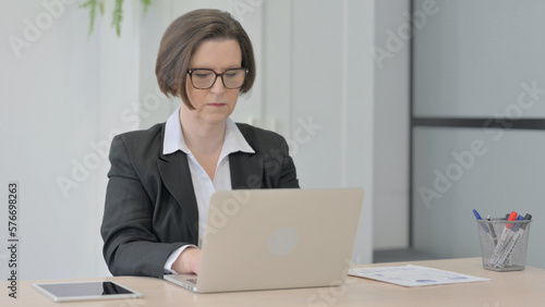 Old Businesswoman Typing on Laptop in Office
